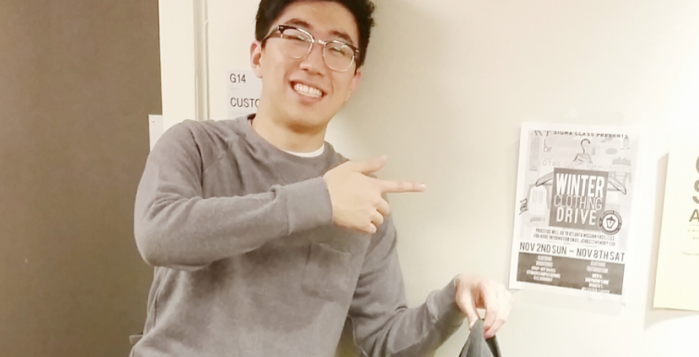 College sophomore Alvin Choi proudly donates a piece of clothing for AKPsi's clothing drive. As service committee chair, Choi hopes that the fraternity's effort will make a change in the community. | Photo by Loli Lucaciu